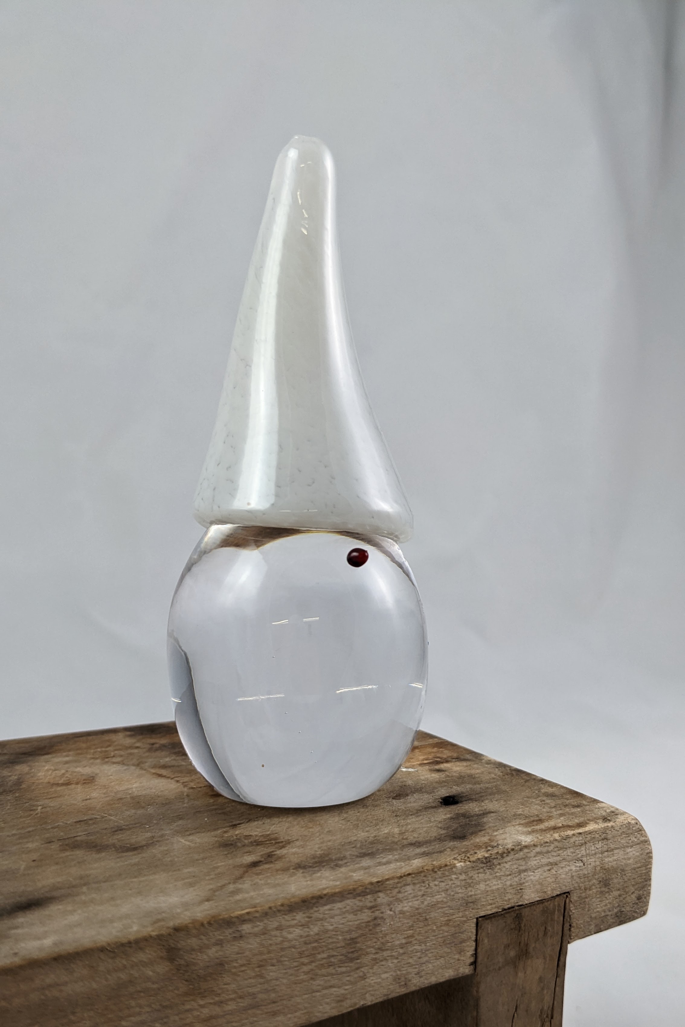glass tomte with a clear body and red nose, cream colored hat.