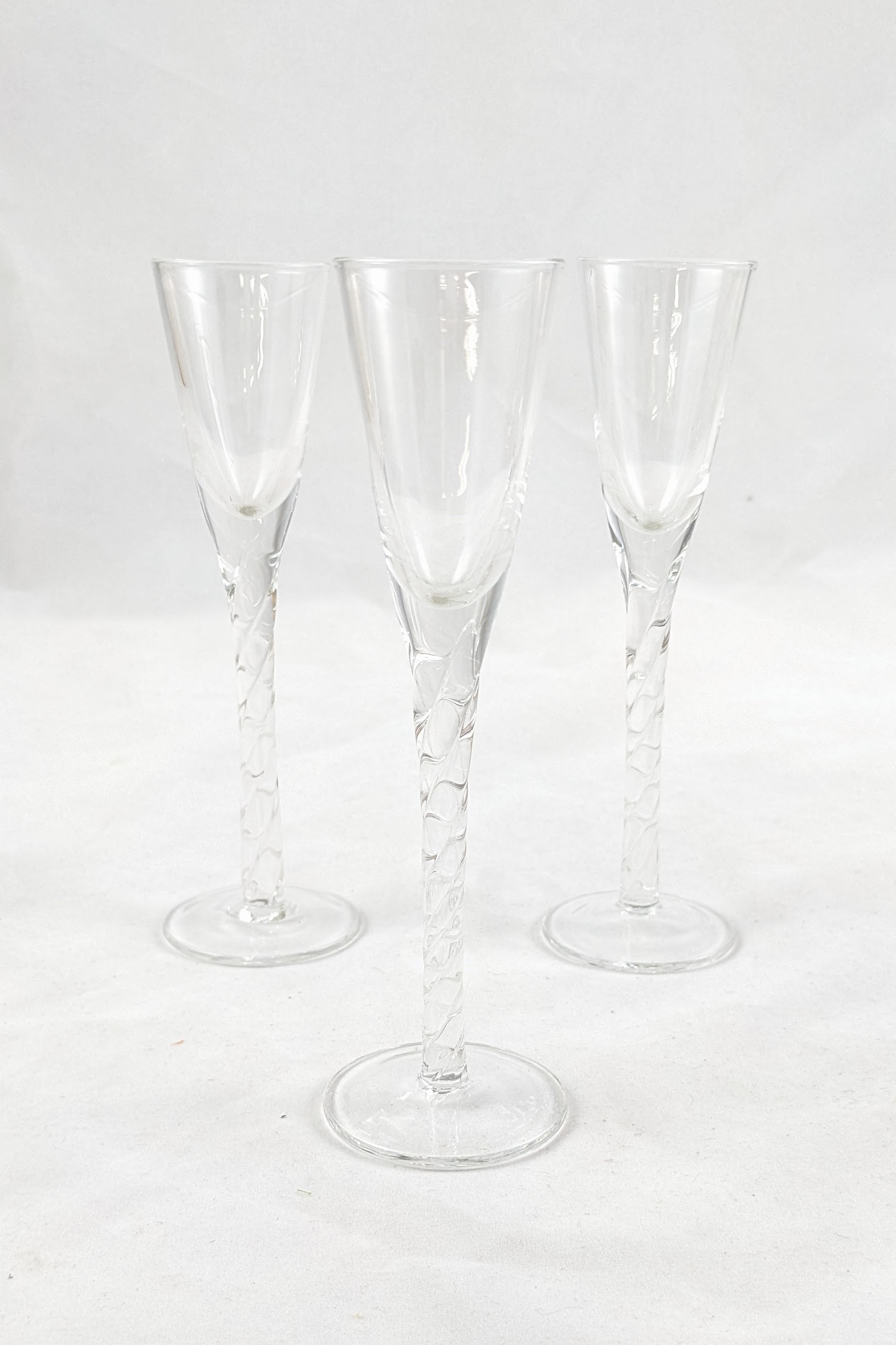Three aquavit glasses with two in the background and one in the foreground. The stem is twisted to give a subtle texture. 