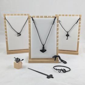 Three necklace displays showing the three variations of necklaces on black leather cords: heart, thor's hammer and a heart. In the foreground is a forged snake ring, snake hairpin and cuff. 