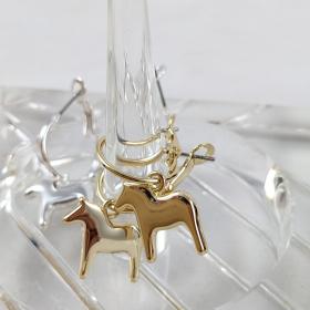 gold colored drop dala horse earrings, with the silver pair blurred in the background